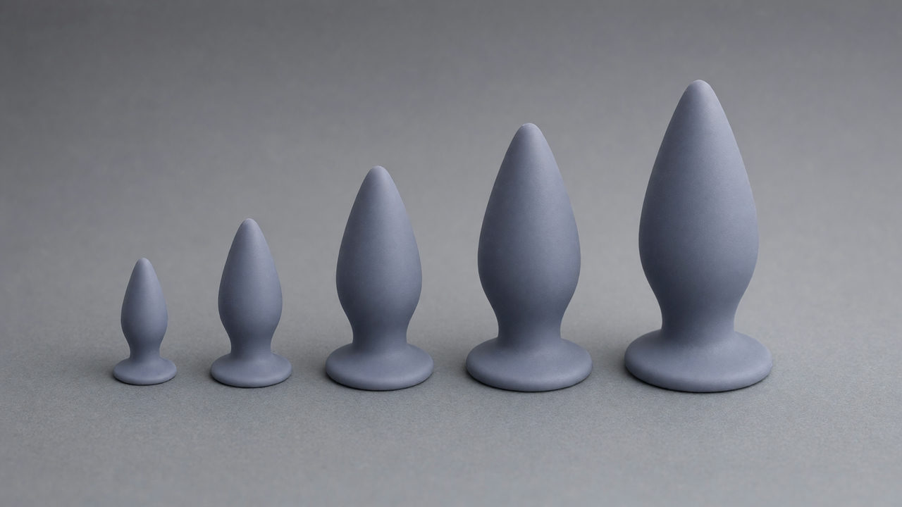 Vier buttplugs op een rij van klein naar groot, elk met een tapse druppelvorm op een smalle hals boven een brede platte voet