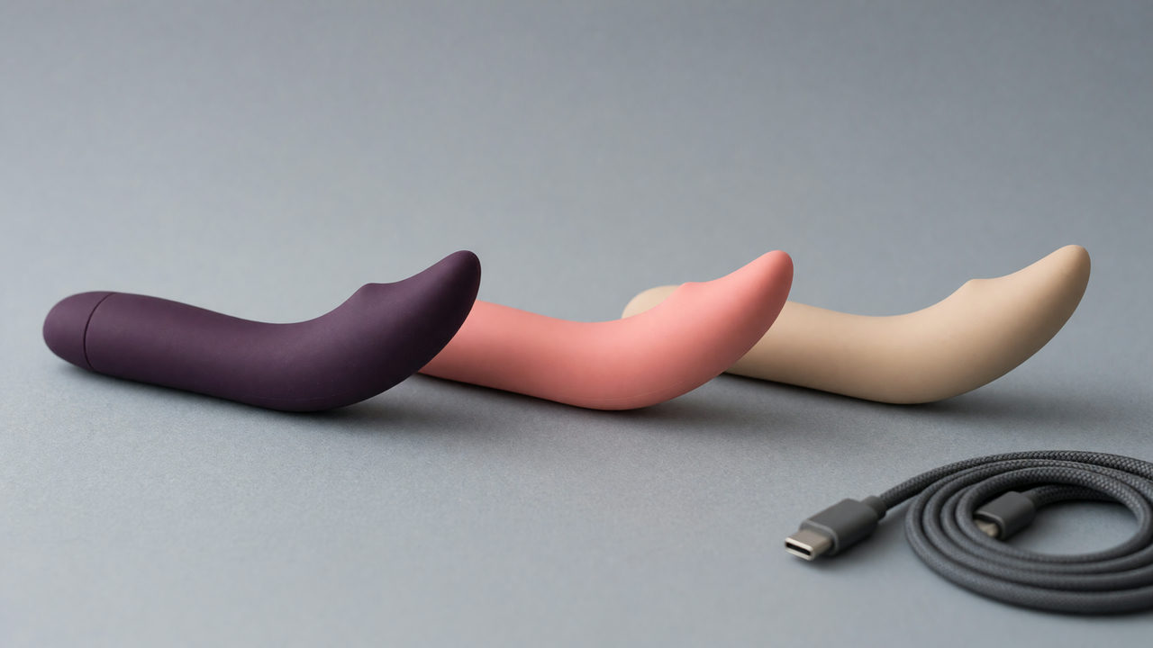 Drie G-spot vibrators naast elkaar, elk met een slanke steel en een omhoog gebogen tip, met een opgerolde oplaadkabel ernaast