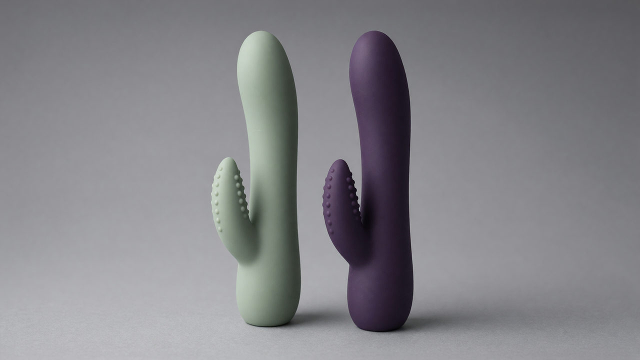 Twee rabbitvibrators rechtop naast elkaar, van iets boven gezien, met bij allebei de gebogen schacht en de kortere tweede arm in beeld