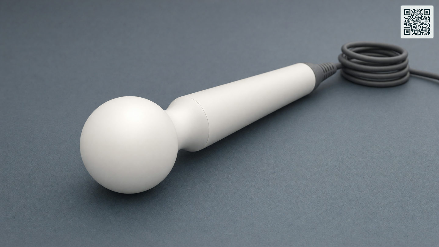 Één wand massager ligt schuin over het beeld, met de grote ronde kop vooraan en een opgerold snoer achterin.