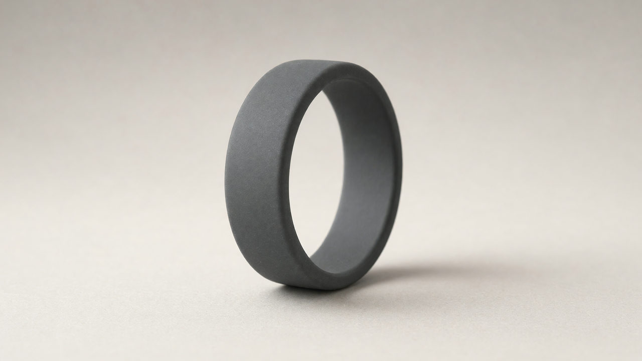Een matte donkergrijze siliconen ring staand op een lichte neutrale ondergrond.