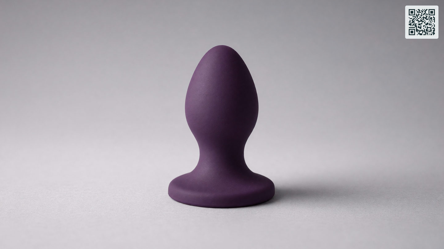 Een grote siliconen buttplug met brede uitlopende voet op een lichte ondergrond
