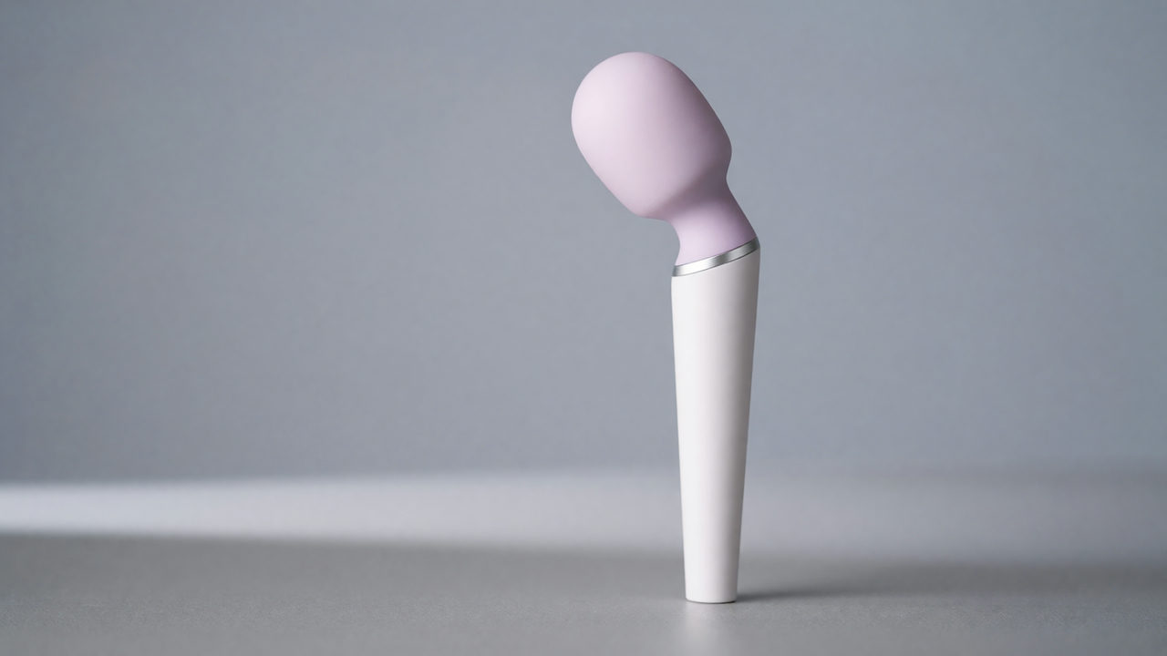 Een witte snoerloze wand massager met ronde siliconen kop op een zachte, neutrale achtergrond